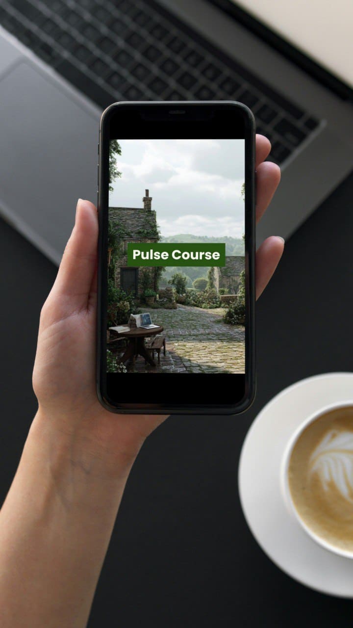 Person holding a smartphone with 'Pulse Course' displayed, laptop and coffee cup in the background